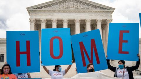 Activists hold up a sign reading Home outside the US Supreme Court