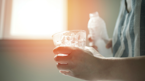 Anonymous hands holding a glass and bottle of water