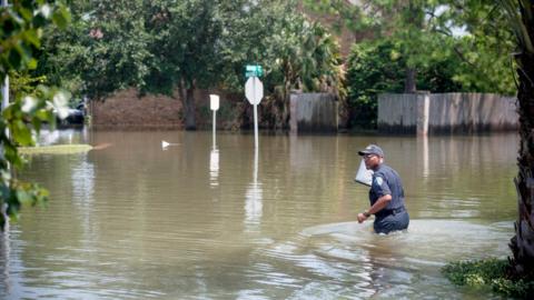 A police officer walks across a flooded street in Port Arthur, Texas, September 1, 2017