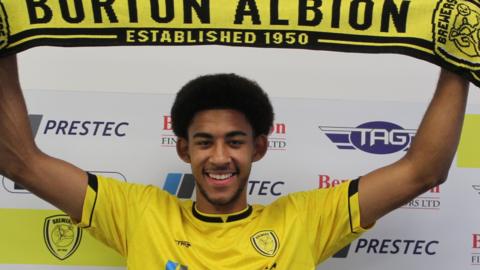 Tyler Onyango holds up a Burton scarf