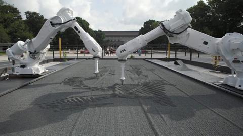 Two robots drawing in grey sand in Ueno Park, Tokyo