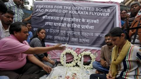 People hold a memorial service at the site of the collapsed flyover in Kolkata