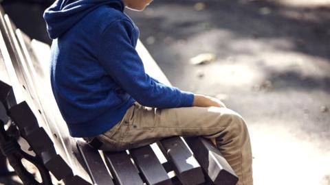 Stock photo of boy on park bench