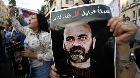 File photo showing a woman holding up a poster of Nizar Banat at a protest against the Palestinian Authority in Ramallah, in the occupied West Bank (2 August 2021)