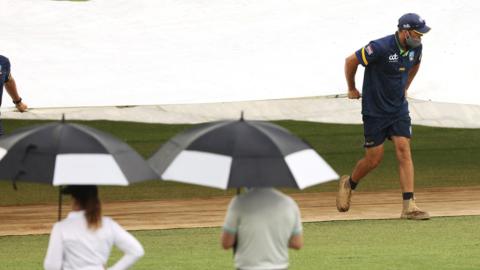 Groundstaff bring covers onto the pitch