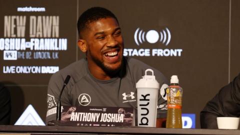 Anthony Joshua laughs at a news conference