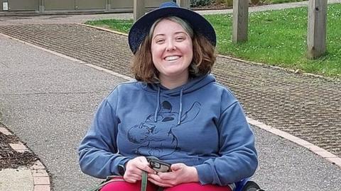 Lucy King in her wheelchair with a black dog on a lead next to her