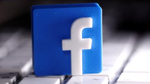 A small 3D-printed Facebook logo sits on a keyboard in this photo illustration