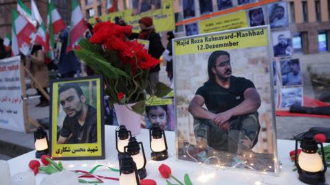 Photos of Majidreza Rahnavard (R) and Mohsen Shekari (L) stand on a table among candles during a demonstration by an exiled Iranian opposition group outside the German Foreign Ministry in Berlin, Germany (12 December 2022)