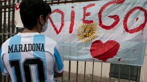 A fan wearing a Maradona Argentina shirt looks at a tribute in Buenos Aires