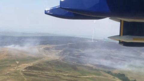 Plane flying over burning moorland