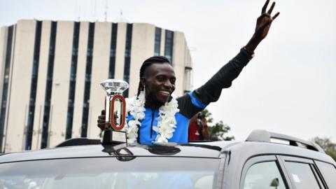 Athlete Francine Niyonsaba shows off her Diamond League trophy on her return to Burundi