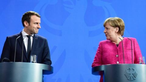 Macron and Merkel sharing a smile during a press conference