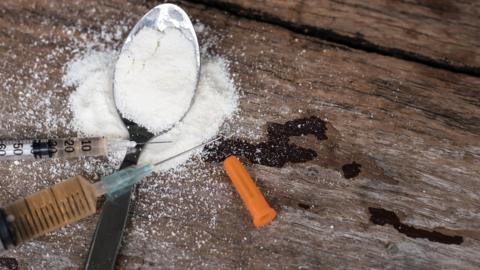 A syringe and spoon with white powder