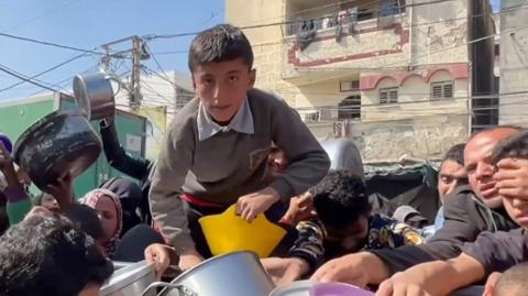 A boy climbing over people for food