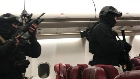 Heavily armed police enter the plane after it returned to Melbourne Airport