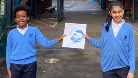 Children holding new school emblem