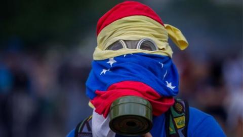 A protester wearing a gas mask is seen during clashes with the Venezuelan National Guard (GNB) in Caracas, Venezuela, on 10 April 2017.