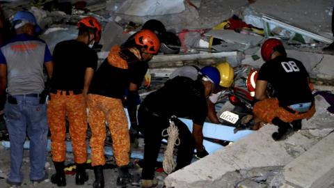 Emergency responders look through rubble of a commercial building following the earthquake