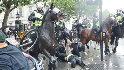 An injured police officers is attended to after falling off her horse