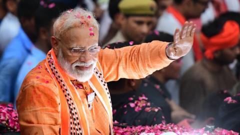 Indian Prime Minister and leader of the Bharatiya Janata Party (BJP) Narendra Modi gestures during a roadshow in Varanasi on April 25, 2019. - Tens of thousands of followers of Indian Prime Minister Narendra Modi packed the streets of his political bastion on April 25 as he stepped up campaigning in the country's marathon election.