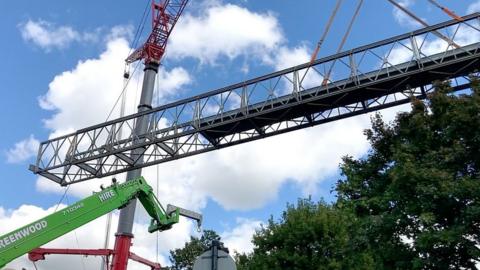 The footbridge being lifted into position