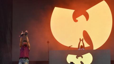 RZA performs in front of a Wu-Tang clan sign