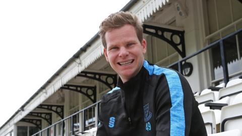 Australia batter Steve Smith smiles while wearing Sussex kit in the stands at Hove