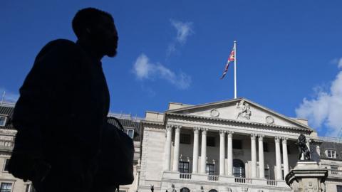 man in shadow in front of bank of england