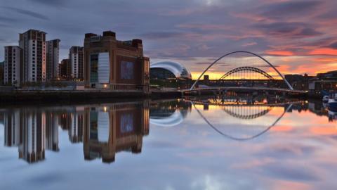 Buildings and bridge on river Tyne in Gateshead reflected on water