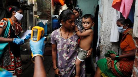 A healthcare worker checks the temperature of a woman in Mumbai, India, July 6, 2020