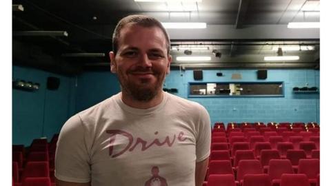 A man standing in front of an empty cinema