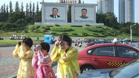 Women in Pyongyang try to protect their faces from the sun. 27 July 2018