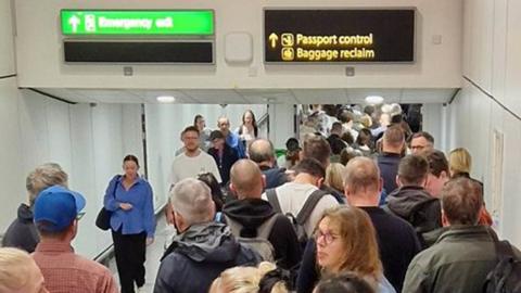 A crowd of people pictured at passport control at Gatwick Airport on 7 May