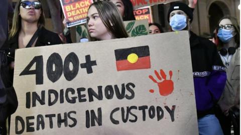 A protester at Sydney's Black Lives Matter march holds up a sign which reads '400 indigenous deaths in custody'