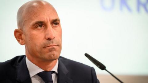 Luis Rubiales sits in front of a microphone