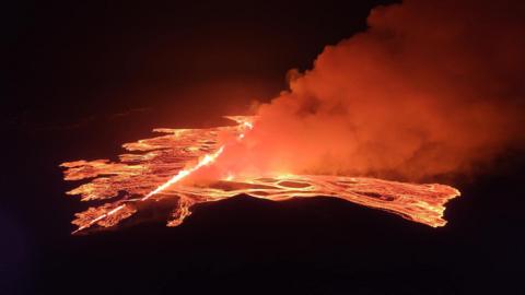 Magma and smoke pour from a fissure in the earth in Iceland