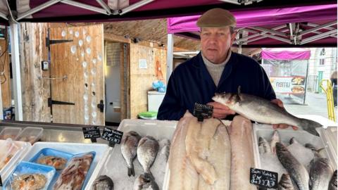 Tim Mead standing behind his fishmonger stall.