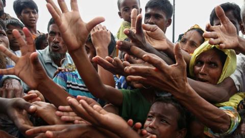 This 30 August 2017 photo shows Rohingya refugees reaching for food aid at Kutupalong refugee camp in Ukhiya near the Bangladesh-Myanmar border