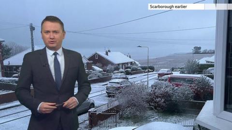Matt Taylor standing in front of a photograph of snow on a street in Scarborough