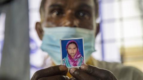 A father holds a picture of his missing daughter at the Dhaka Medical College Hospital in Dhaka, Bangladesh, 10 July 2021