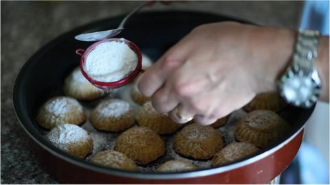 Date maamoul being topped with icing sugar