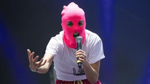 Nadezhda Tolokonnikova of Pussy Riot wearing pink balaclava on stage in 2018