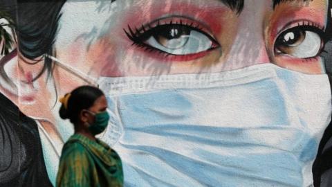 A woman walks past a graffiti of a girl wearing a protective mask amidst the spread of the coronavirus disease (COVID-19) in Mumbai, India, October 23, 2020.