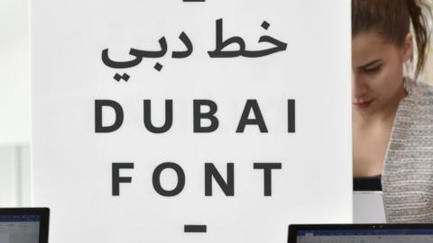 An attendee looks at computers showing the 'Dubai Font'