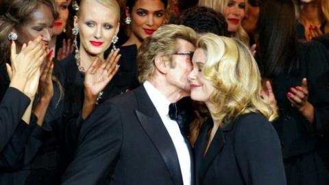 Yves Saint-Laurent (L) kisses Catherine Deneuve in 2002 during his last fashion show