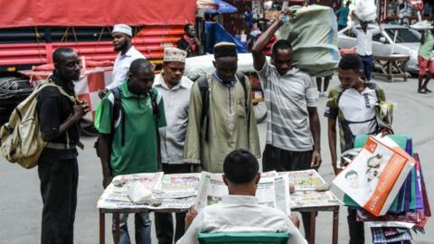 People look at newspapers without adhering to the rules of social distancing despite the confirmed COVID-19 coronavirus cases in Dar es Salaam, Tanzania, on 16 April 2020