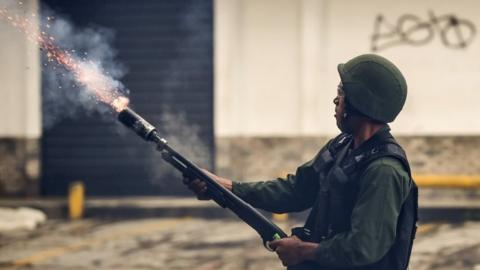 A member of the national guard fires a tear gas grenade at opposition demonstrators during clashes in Caracas on July 28, 2017