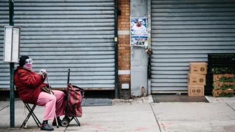 A woman wearing a scarf and goggles wait for a bus to arrive in a bus stop in Brooklyn