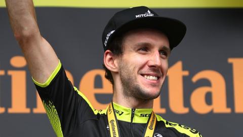 Simon Yates smiles on the podium after winning a stage of the 2019 Tour de France